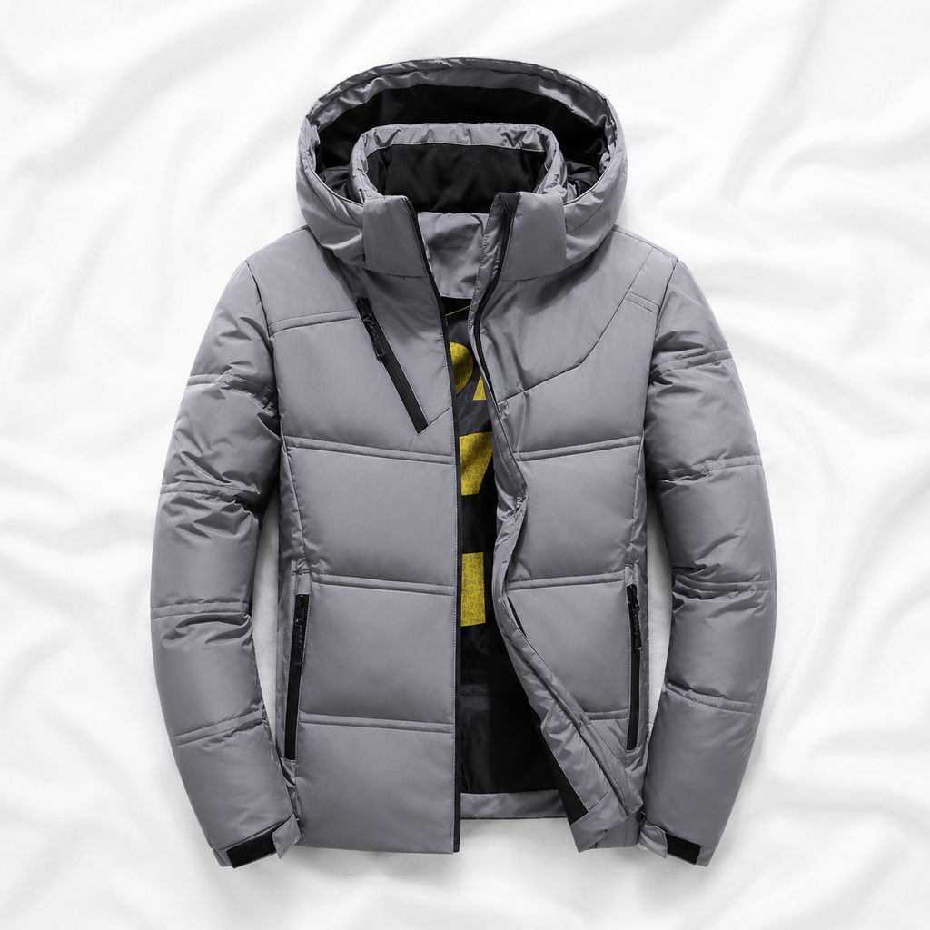 Light grey hooded puffer jacket displayed on a soft white cloth background, showcasing its insulated design, quilted construction, full front zip and practical winter outerwear style.