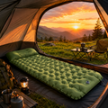 Inflatable camping air mattress set up inside a tent on green grass at sunset, providing comfortable support for overnight camping and outdoor adventures.